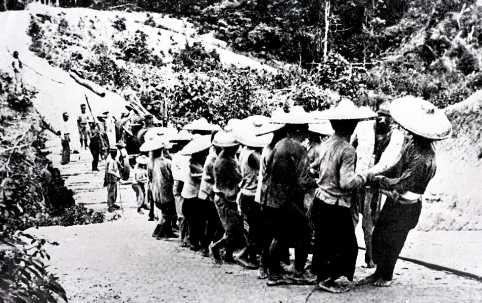 1913: Chinese coolies strain to haul a boiler up a youthful Oilfield Road - a place where malarial jungle killed men and lack of communications killed progress